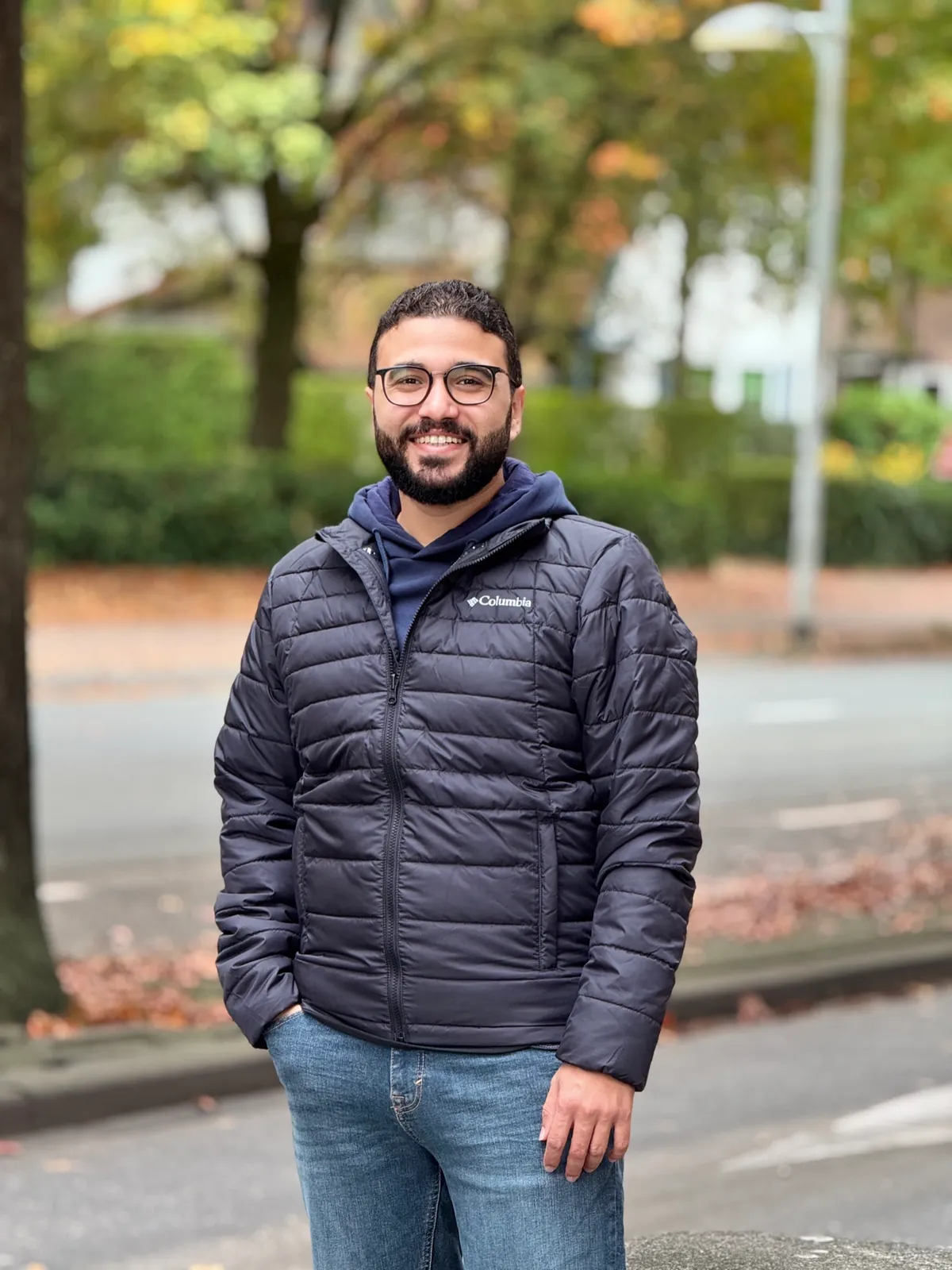 Mohamed smiling, standing on an autumn street in Utrecht
